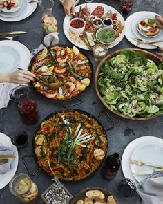 a table topped with lots of different types of food next to plates and bowls filled with salads