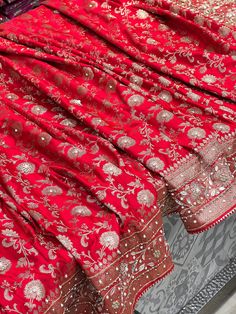 Expertly crafted from Banarasi silk, this Red Saree showcases a small floral pattern with delicate hand embroidery including moti, cuddana, stones, and gotapatti. Zardosi adds a touch of elegance to this traditional saree, making it a perfect choice for any special occasion. Festivals Semi-stitched Sharara With Motifs, Embroidered Banarasi Silk Choli For Navratri, Semi-stitched Katan Silk Traditional Wear With Intricate Embroidery, Semi-stitched Banarasi Silk Choli With Resham Embroidery, Unstitched Jamawar Choli With Intricate Embroidery, Ceremonial Choli With Resham Embroidery For Diwali, Diwali Ceremonial Choli With Resham Embroidery, Intricate Embroidery Banarasi Silk Lehenga, Festive Resham Embroidered Jamawar Lehenga