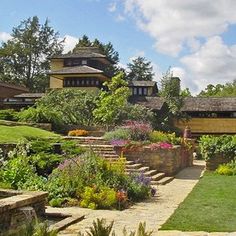 an outdoor garden with steps leading up to the house in the distance and flowers growing on the lawn