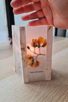 a hand is holding up a small card with flowers on it, and the inside of the card has been folded