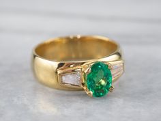 Handsome and understated, this emerald and diamond ring has a timeless design. The emerald is vibrantly green with excellent clarity. The diamonds don't overwhelm the center stone and instead enhance it with just the right amount of sparkle. Highly versatile, this ring is a true classic! Metal: 18K Yellow Gold Gem: Emerald .78 Carats Gem Measurements: 7.0 x 5.0 mm, Oval Accents: 2 Diamonds totaling .42 Carats, J in Color, VS in Clarity Ring Size: 6.50 Marks: "14K MS(C)" Stamped on the inside band Timeless Green Diamond Ring With Accents, Timeless Green Rings With Diamond Accents, Timeless Green Diamond Ring With Brilliant Cut, Timeless Baguette Cut Green Emerald Ring, Timeless Green Baguette-cut Emerald Ring, Timeless Green Baguette Cut Emerald Ring, Timeless Green Emerald Ring With Brilliant Cut, Emerald Ring Design, Antique Rings Vintage