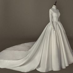 a white wedding dress on display in front of a gray background with a mannequin