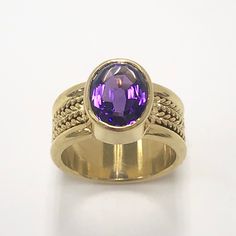 Amethyst ring/03 The playful design is perfect for adding a touch of whimsy to any formal attire, while still maintaining a handsome elegance. Unlike CAD-produced rings made by pouring liquid metal into a mold, this ring is hand-forged from a solid piece of metal. This darling features classic geometric shapes and bold colors. Amethyst's magic intense purple, holding center stage, set in lasting 18 karat gold.  Amethyst: 3.50 ct, 8 x 10 mm   Weight: 13 g      9 mm wide shank Material: 18 karat yellow gold Elegant Sapphire Ring With Tanzanite And Polished Finish, Formal Purple Sapphire Ring With Gemstone Accents, Luxury Purple Ring With Bezel Setting, Elegant Amethyst Rings With Gemstone Accents, Formal Gold Sapphire Ring With Gemstone Accents, Elegant Gold Tanzanite Rings, Elegant Gold Rings With Tanzanite, Formal Purple Oval Ruby Ring, Formal Oval Tanzanite Ring