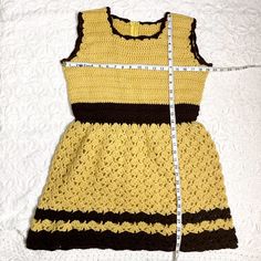 Beyond adorable fit and flare handmade crocheted mini dress in gold and brown. Sleeveless fitted top with back zipper. Open crochet skirt that's semi-full. Zipper is nylon. Worsted weight yarn. Note: it's pinned to fit the dress form. Material / acrylic yarn Care / machine wash For accurate fit, please compare measurements to a similar garment that fits you well. Make allowance for clothes underneath and to allow garment to drape properly. Size on tag / no tags, fits like a mediumish Measurement Fitted Sleeveless Crochet Lace Dress, Sleeveless Crochet Lace Mini Dress, Fitted Sleeveless Crochet Mini Dress, Fitted Sleeveless Mini Dress With Crochet, Fitted Brown Sleeveless Mini Dress, Fitted Brown Crochet Top For Spring, Fitted Crochet Lace Top, Fitted Crochet Lace Top Mini Length, Fitted Yellow Crochet Dress