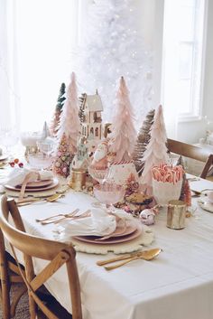 a dining room table set for christmas with pink trees and candy canes on it