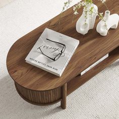 a coffee table with two vases and a magazine on it in front of a white rug