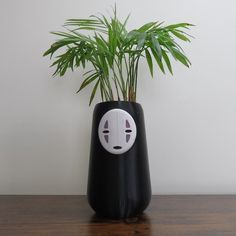 a plant in a black vase with a white face on it