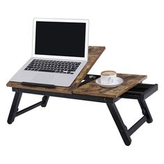 a laptop computer sitting on top of a wooden table next to a cup of coffee