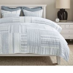 a bed with blue and white comforter in a bedroom next to a night stand