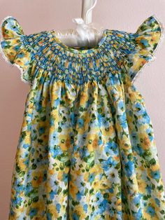 "This adorable floral print bishop-style dress is made with a Robert Kaufmann London Calling lawn. It is smocked in blue to match some of the flowers in the fabric. Made with angel sleeves, this dress is perfect for warm weather wearing. All of my dresses have a generous 4-5\" hem, and all seams are French seams. Finished lengths from the shoulder to the hem edge are: 3 Months 14\" 6 Months 15\" 9 Months 16\" 12 Months 17\" 18 Months 18\" 24 Months 19\" 2 Toddler 21\" 3 Toddler 22\" 4 Toddler 23 Smocked Bishop Dress, Angel Sleeves, Angel Sleeve, London Calling, French Seam, Style Dress, Toddler Girls, Watercolor Print, 3 Months