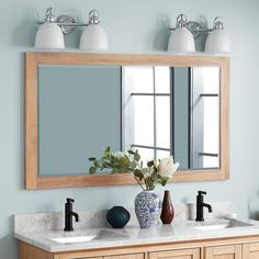 a bathroom vanity with two sinks and a large mirror above it, in front of a blue wall