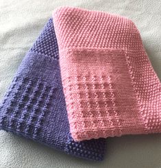 three knitted dishcloths laying on top of each other, one pink and the other blue