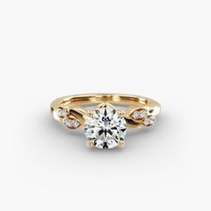 a yellow gold engagement ring with diamonds on the band and a round brilliant center stone