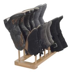 six pairs of boots are lined up on a wooden stand