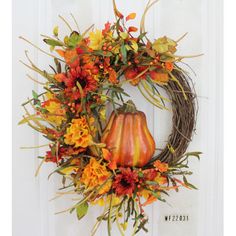 a wreath with orange and yellow flowers is hanging on the front door's white door