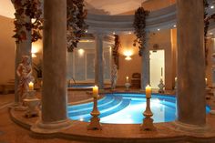 an indoor swimming pool surrounded by columns and candles