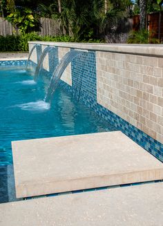 an outdoor swimming pool with waterfall and tiled walls