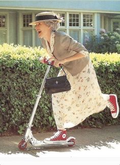 an old woman riding a scooter with a purse on the handlebars