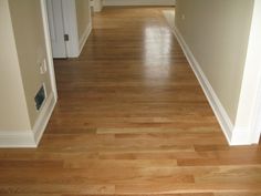 an empty hallway with hard wood floors and white trim