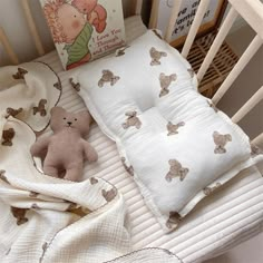 a baby crib with a teddy bear, book and blanket on top of it