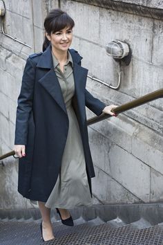 a woman is walking up some stairs with her hand on the rail and smiling at the camera