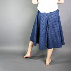 a woman in a white shirt and blue skirt posing for the camera with her hands behind her head