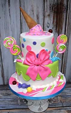 a multi - tiered cake decorated with candy, lollipops and an ice cream cone