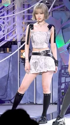 a woman standing on top of a stage wearing short shorts and knee high black boots