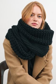 a woman sitting in a chair wearing a black knitted cowl scarf over her neck