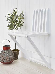 a white chair sitting next to a potted plant on top of a wooden floor