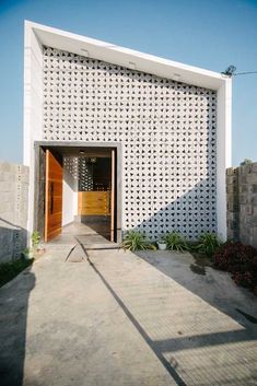 an entrance to a white building with perfored screens on the front and side