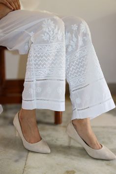 Elevate your leisure and yoga sessions with our effortlessly chic cotton pants. Crafted for comfort with a relaxed fit, these pants are adorned with vintage chikankari embroidery featuring contemporary motifs, adding a touch of artistic flair to your ensemble.  Delicate lace inserts accentuate the design, while the option of white or black hues ensures versatility in styling. Embrace relaxation in style with these timeless yet trendy pants. Comes with Pockets. Colours - White and Black Sizes - Sizes -  S -  waist stretched fits upto 40 M - waist stretched fits upto 42 L -  waist stretched fits upto 44 XL - waist stretched fits upto 46 XXL - waist stretched fits upto 48/50 prewashed. preshrunk. loris cotton pants. White Trouser Design, Chikankari Embroidery, Trendy Pants, Trouser Design, Womens Trousers, Lace Insert, Pants Design, Cotton Pants, Work Pants