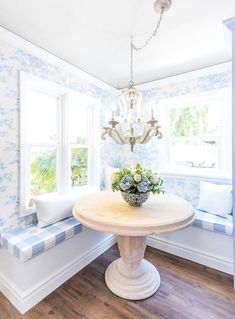 a dining room with blue and white wallpaper, chandelier and window seat