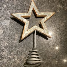 a metal star on top of a table next to a spiral wire holder with an object in the middle