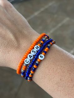 This stack is perfect for all those Soccer Moms, Football moms, baseball moms, etc! Customize them with your team colors, player name, number, school name, mascot, etc!  All bracelets are handmade with stretchy elastic string to allow the bracelet to stretch over your hand and fit snug around your wrist. Excessive stretching or liquids (such as water, perfume, lotions, etc.) may breakdown the elastic and cause the bracelet to break.  Please be sure to provide personalization details and check al Number Bracelets, Bracelet Maker, Military Bracelet, Football Moms, Soccer Moms, Team Bracelets, Baseball Bracelet, Football Bracelet, Water Perfume