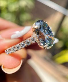 a close up of a person's hand holding a ring with a diamond on it