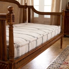 a wooden bed frame sitting on top of a hard wood floor next to a window