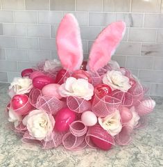 a basket filled with pink and white easter eggs sitting on top of a marble counter