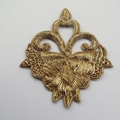 an ornate gold brooch with intricate filigrees and leaves on the side