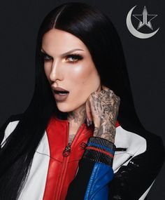 a woman with long black hair and tattoos on her arm wearing a red, white and blue jacket