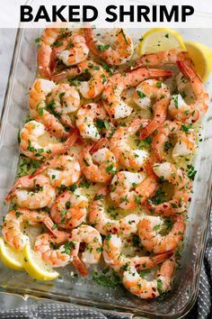 a glass casserole dish filled with shrimp and garnished with lemon wedges