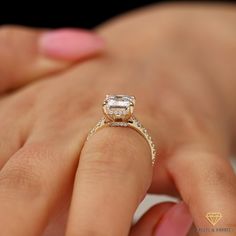 a woman's hand holding an engagement ring with a diamond in the center and two rows of diamonds on each band