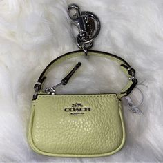 a small yellow purse with a key chain hanging from it's side on a white furnishing