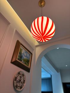 a red and white striped lamp hanging from the ceiling in a room with pictures on the wall