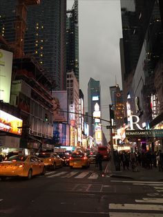 a city street filled with lots of traffic and tall buildings in the background at night