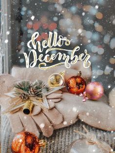 a christmas card with the words hello december written on it and ornaments in front of a window