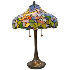 a table lamp with a colorful glass shade on the base and beaded bells attached to it