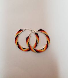 fire colours beaded hoop earrings. 1.5 in hoop 2 in diameter with beadwork. made with size 15 seed beads. Hoop Beaded Earrings With Spacer Beads, Multicolor Hoop Beaded Earrings With Spacer Beads, Multicolor Beaded Hoop Earrings With Spacer Beads, Multicolor Hoop Jewelry With Spacer Beads, Orange Hoop Earrings With Colorful Beads, Multicolor Small Hoop Jewelry With Spacer Beads, Orange Hoop Beaded Earrings As Gift, Orange Beaded Hoop Earrings As A Gift, Orange Small Hoop Earrings With Ear Wire