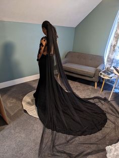 Bride in bridal studio standing showing her back with a black wedding gown that has a train and a long black wedding veil. Alternative Wedding Dress