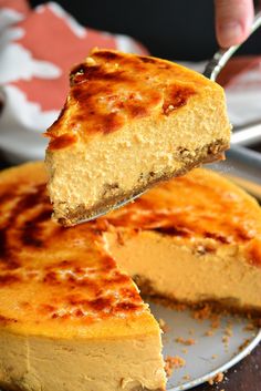 a piece of cheesecake being lifted by a fork from a plate with another slice on it